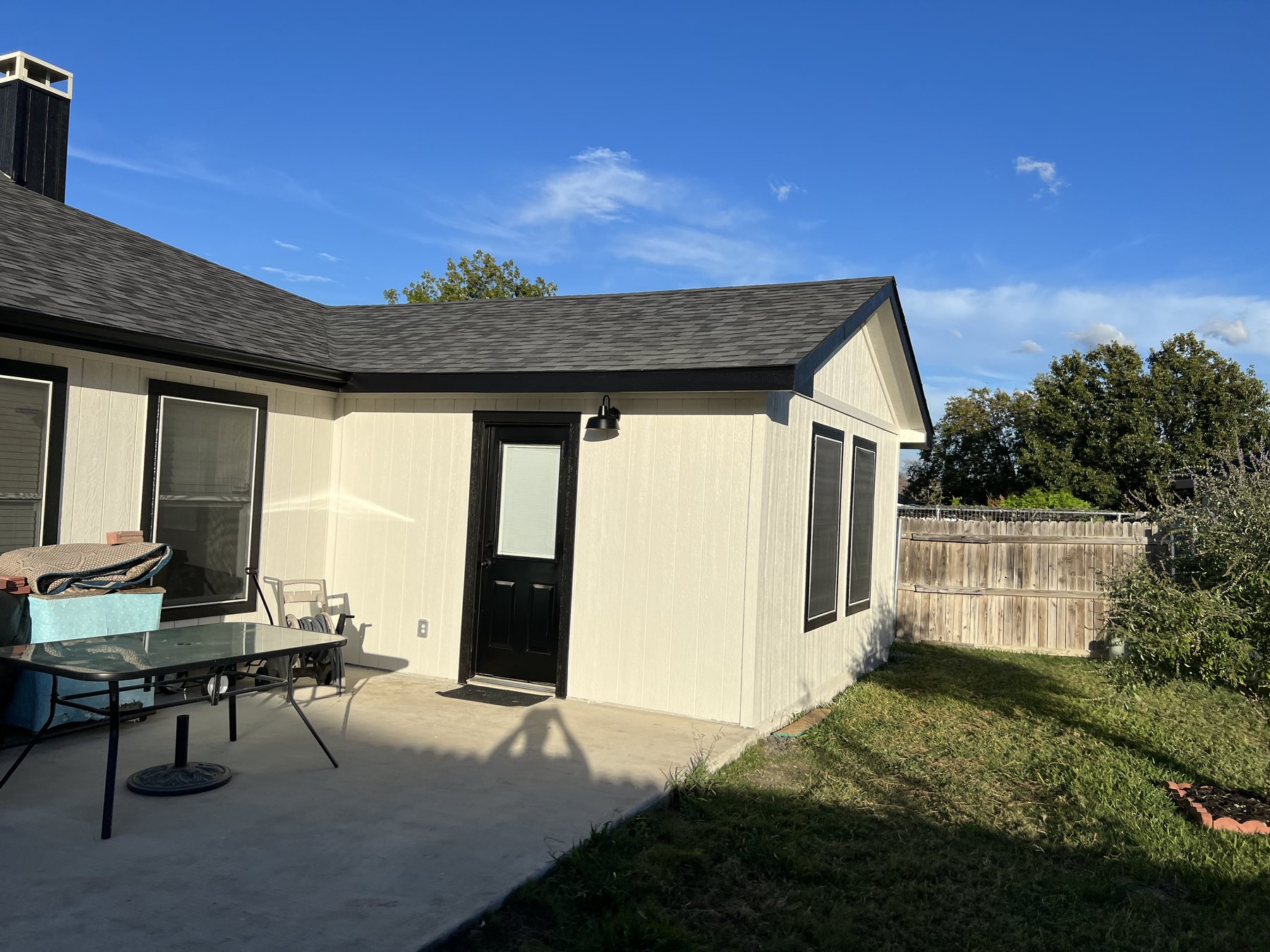 Finished patio addition with new siding, black door, and clean exterior trim
