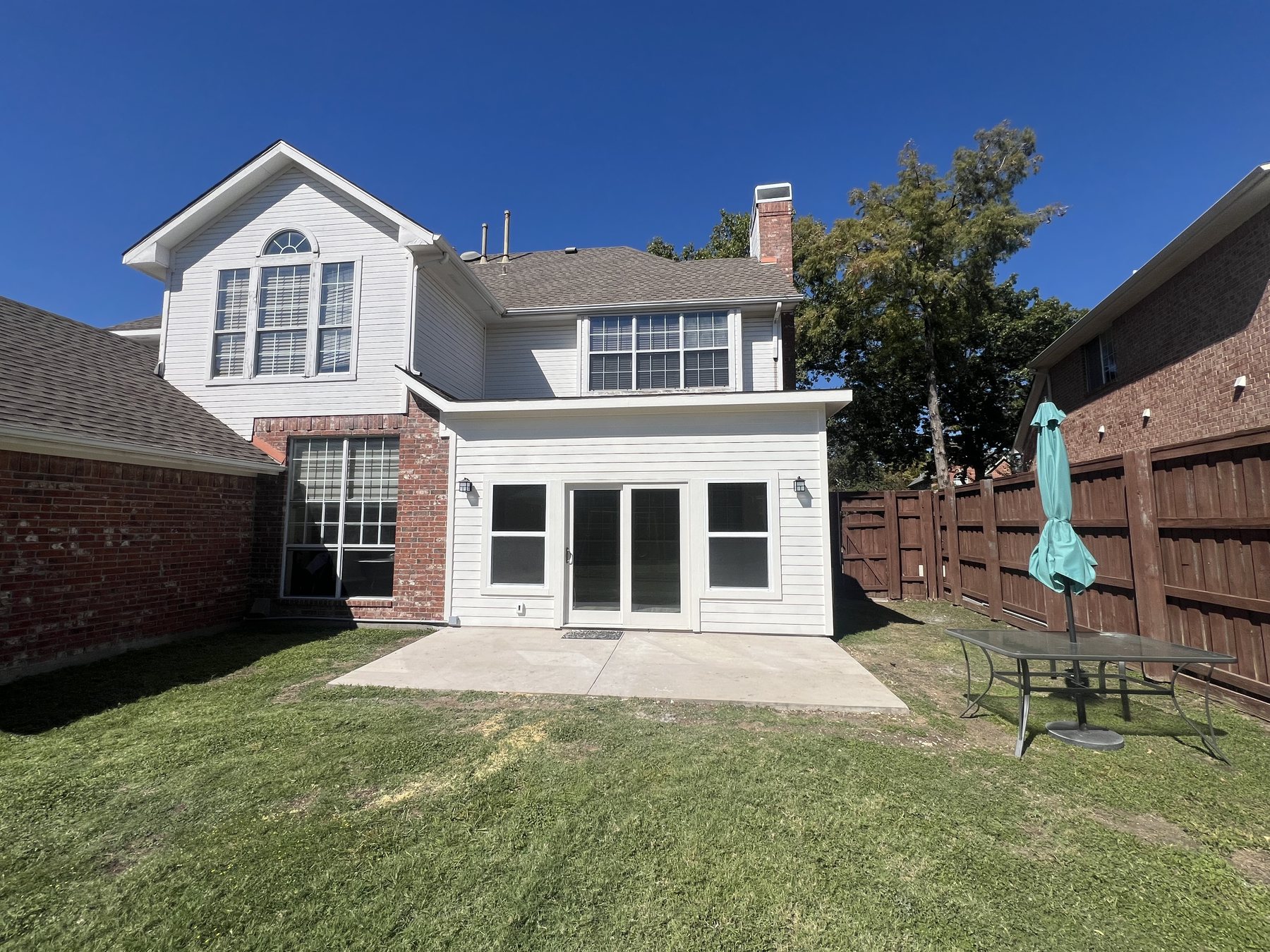 Completed sunroom addition from the backyard with new doors, windows, and concrete patio