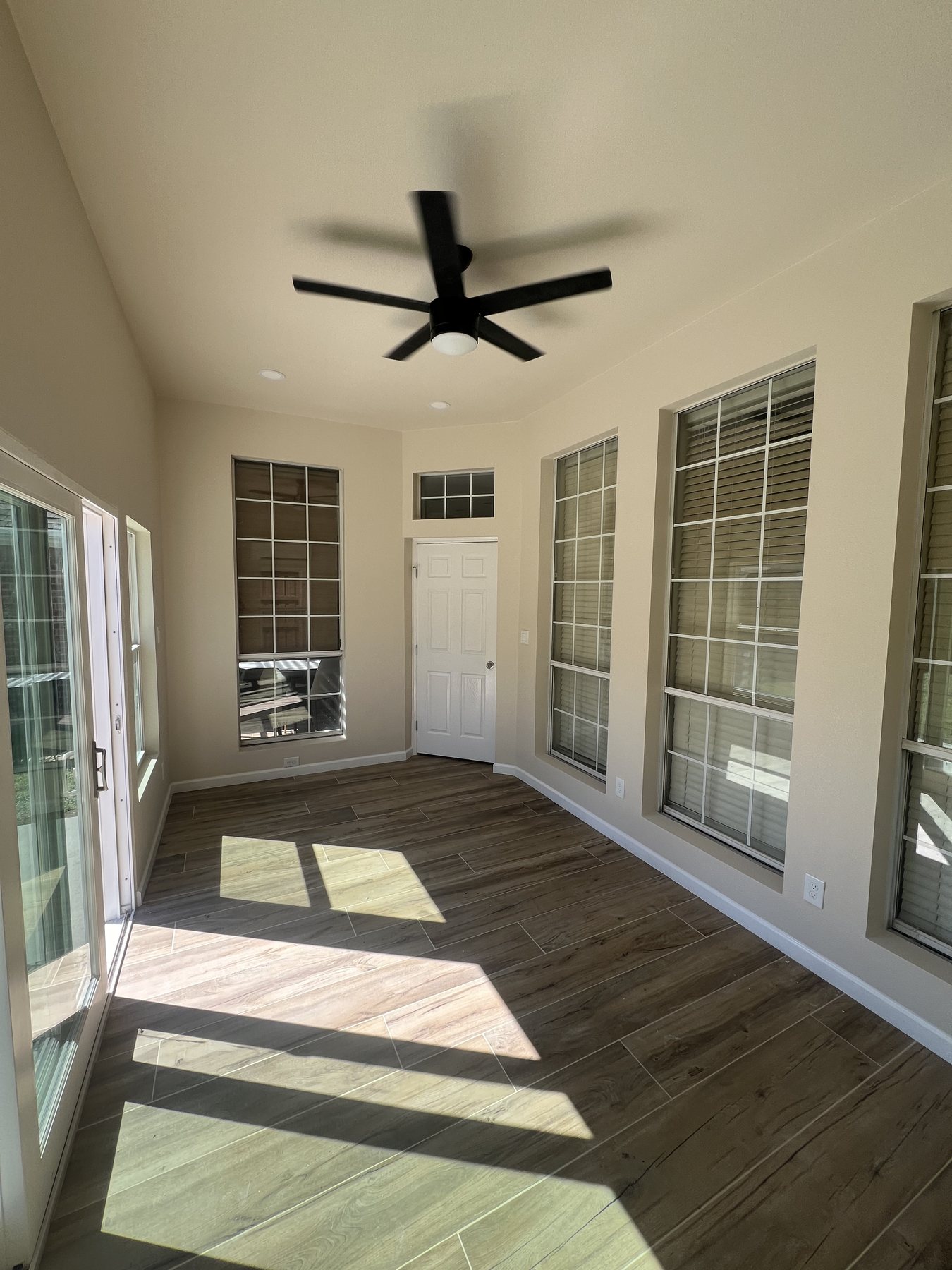 Finished sunroom interior with French doors, large windows, and ceiling fan
