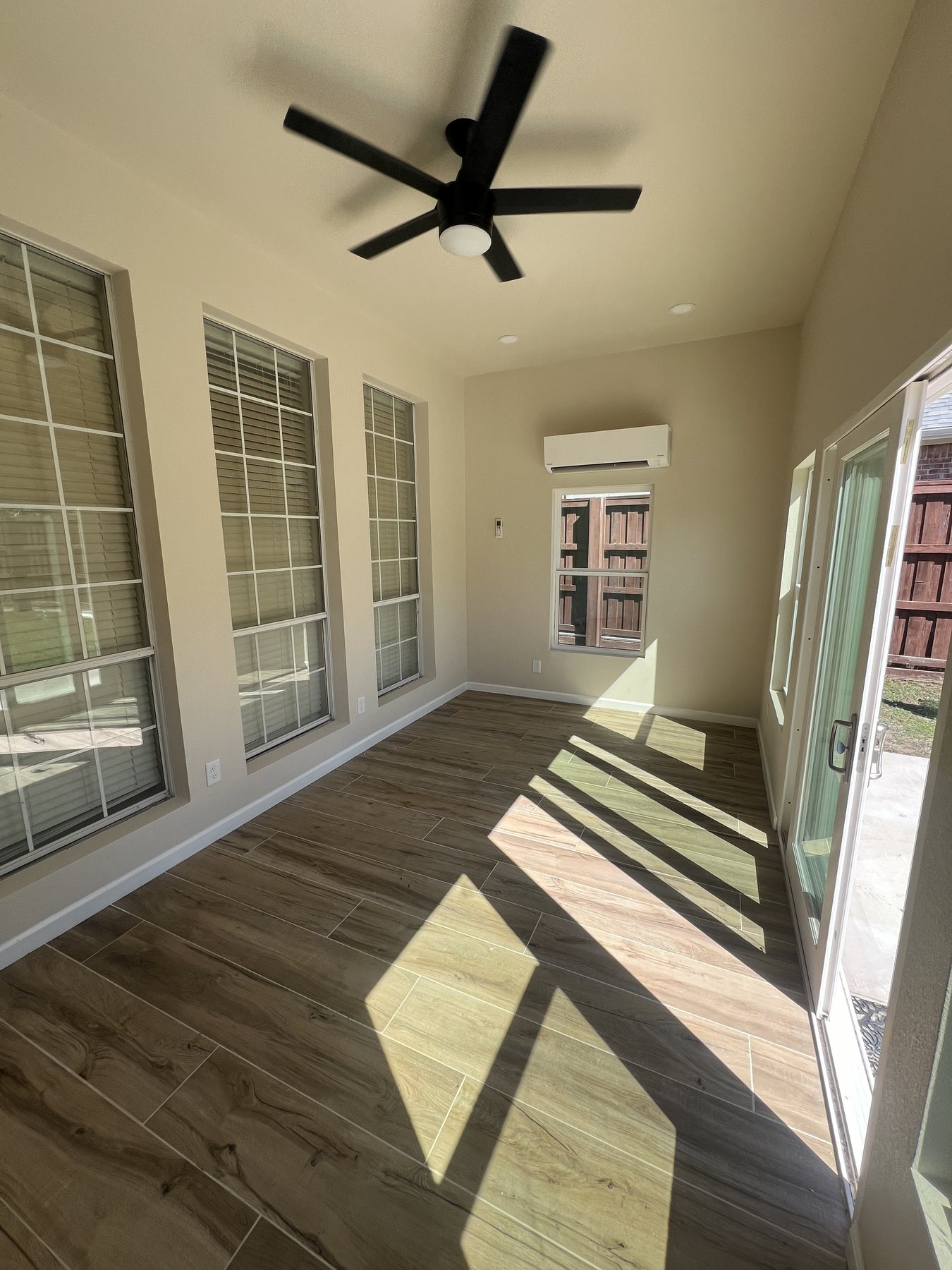 Finished sunroom interior showing window wall, flooring, and ceiling fan