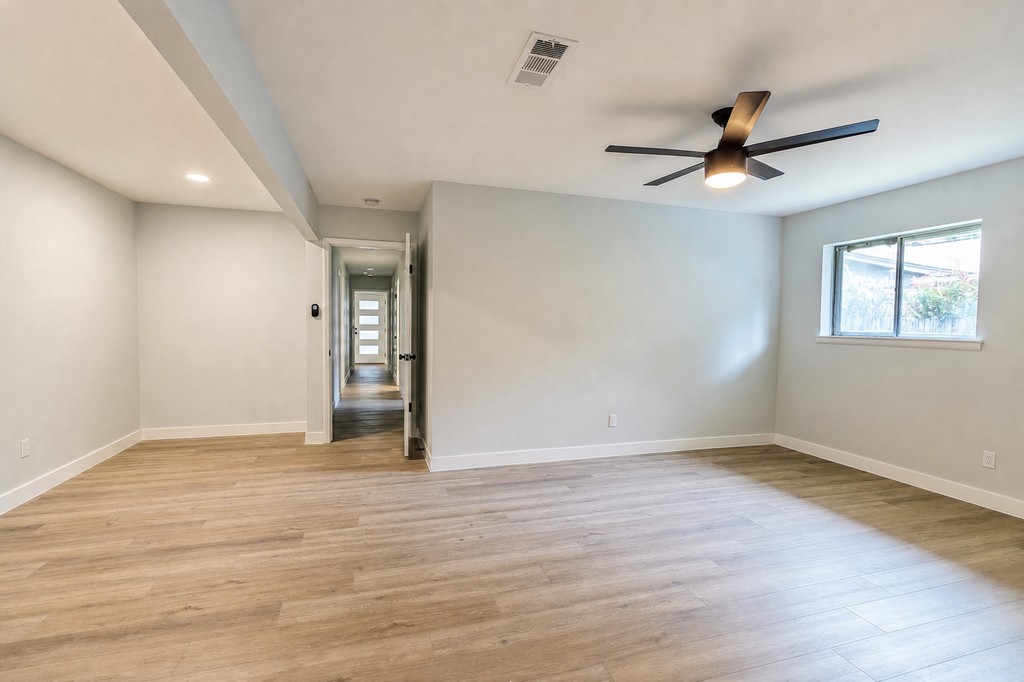 Finished living room with new flooring, trim, paint, and ceiling fan