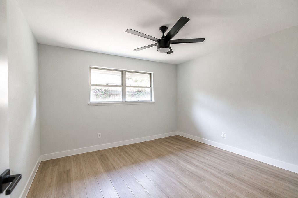 Finished secondary room with new flooring, paint, trim, and ceiling fan