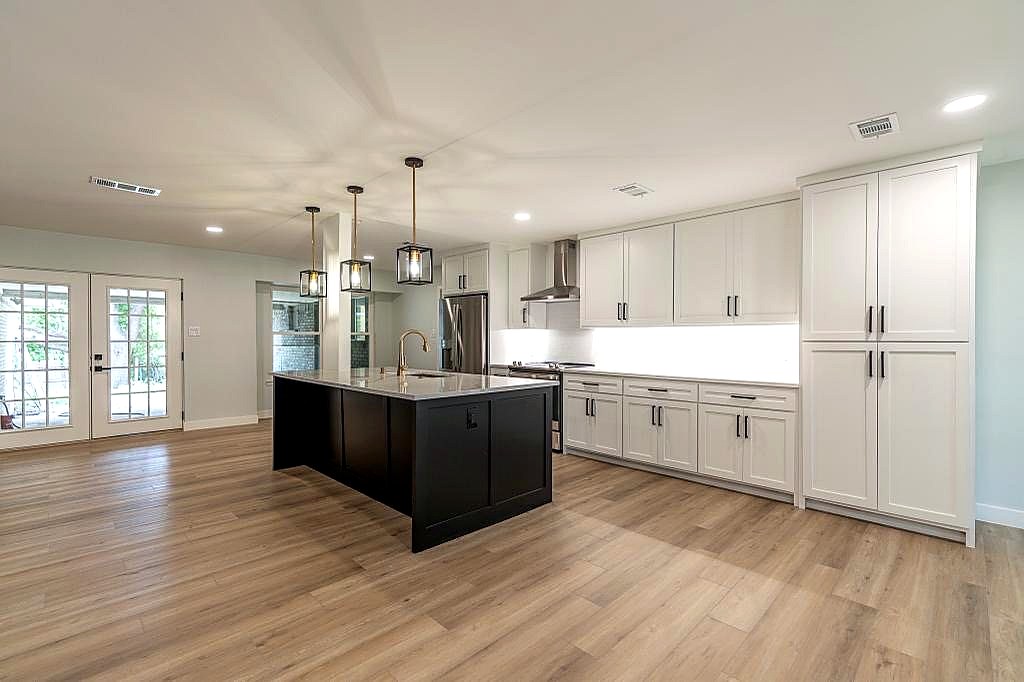 Renovated kitchen with large island, white cabinetry, and updated lighting
