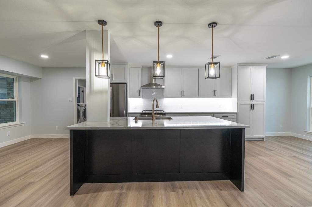 Kitchen island detail with pendant lighting, sink, and waterfall-style countertop