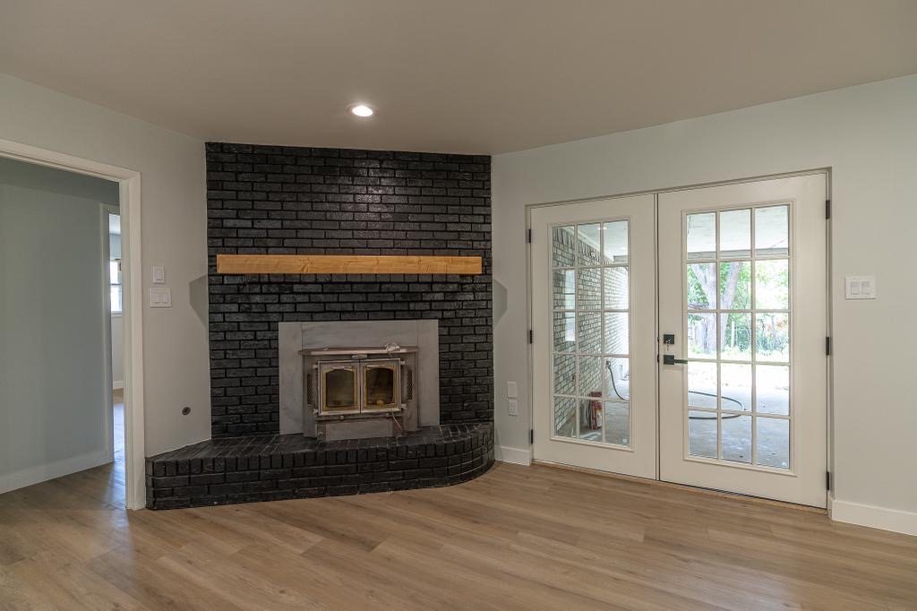 Updated fireplace wall with dark tile surround and French doors