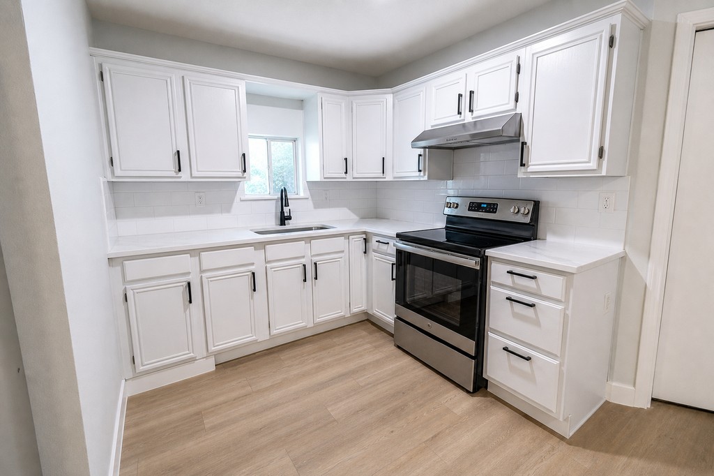 Finished white kitchen with stainless appliances and light flooring