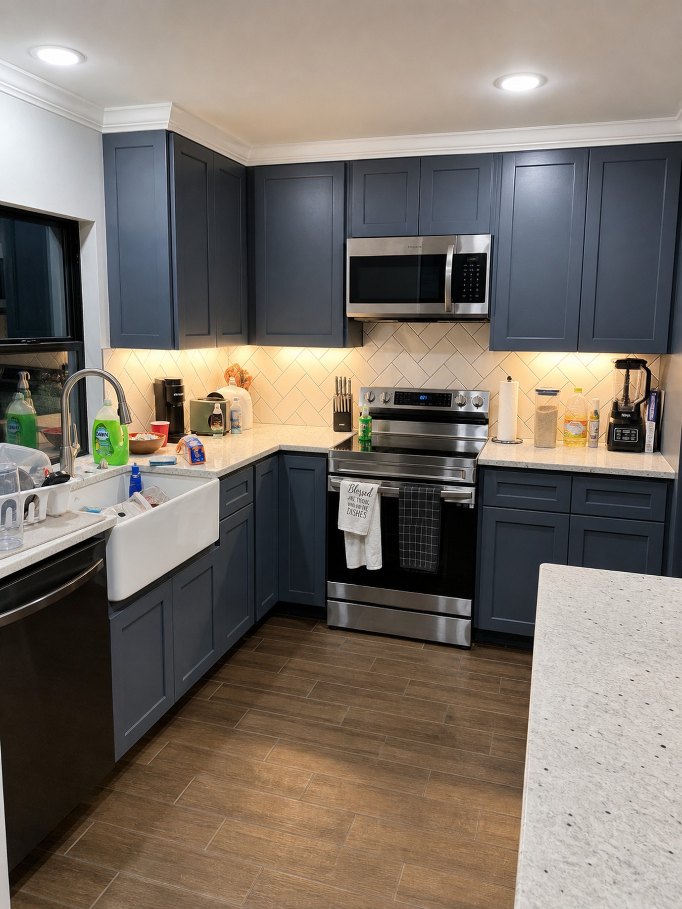 Blue gray kitchen cabinetry with updated appliances and backsplash lighting