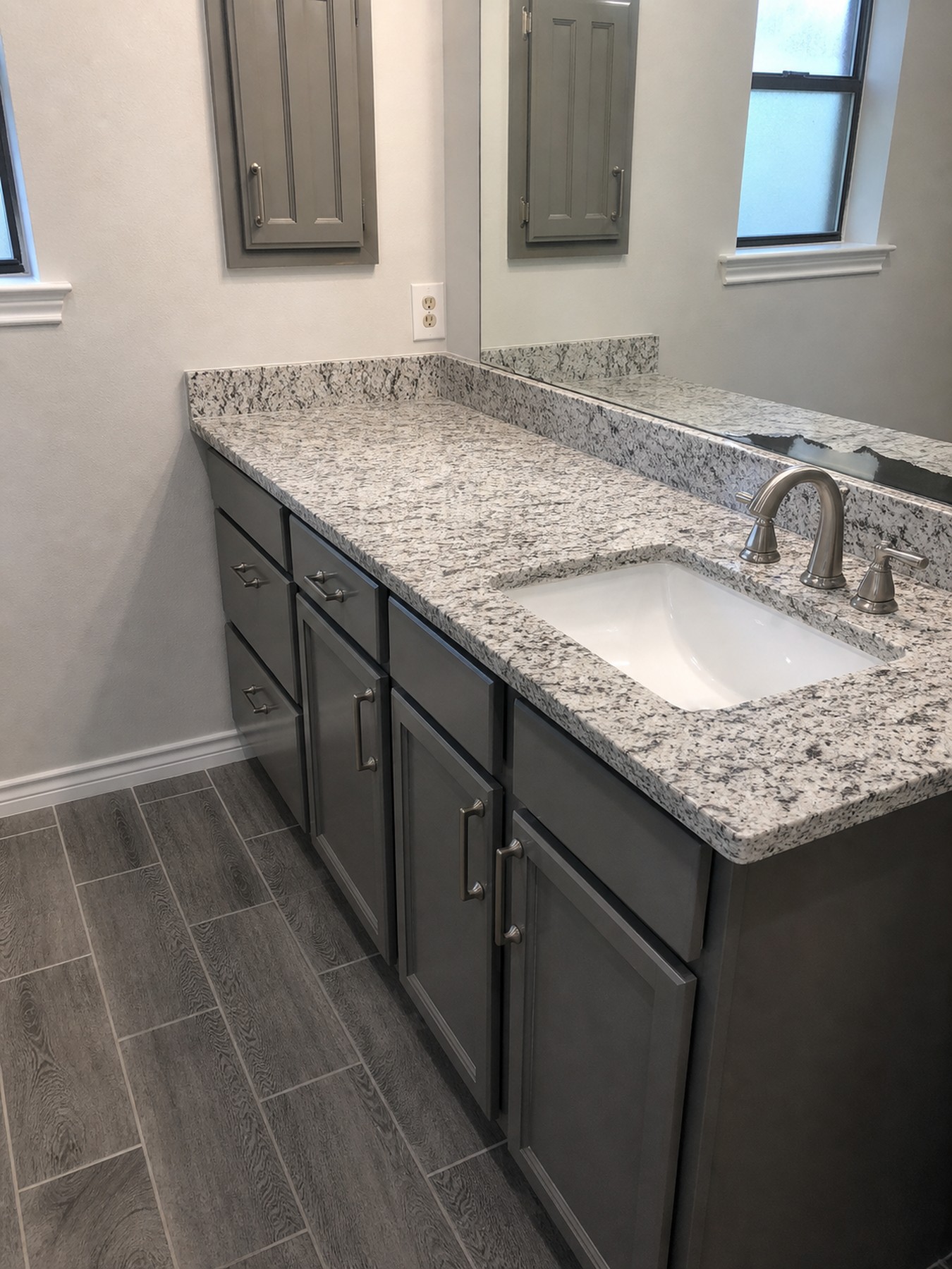 Bathroom vanity detail with dark cabinetry and stone countertop