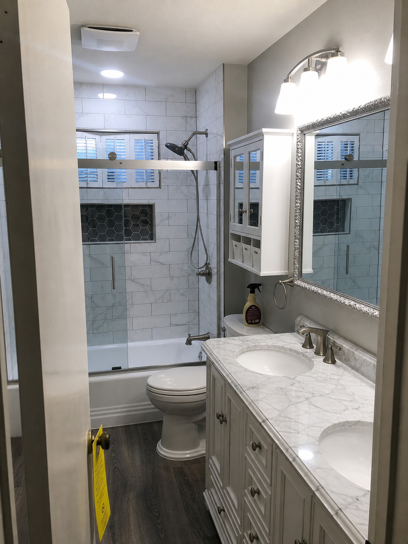 Finished bathroom view with glass shower, vanity, and tile surround