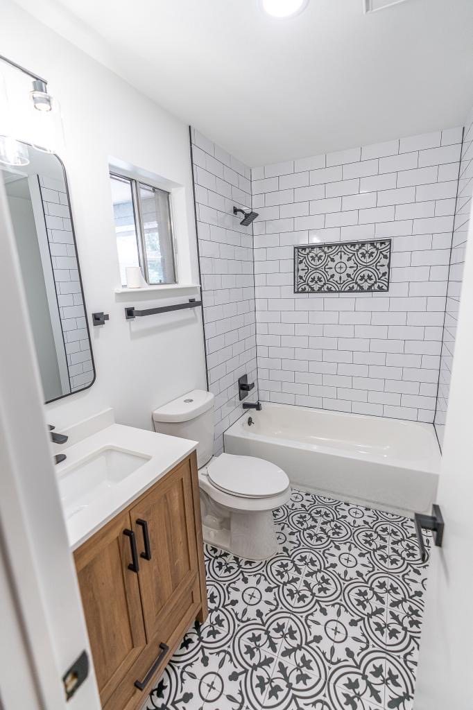 Bathroom remodel with patterned floor tile, subway shower tile, and wood vanity