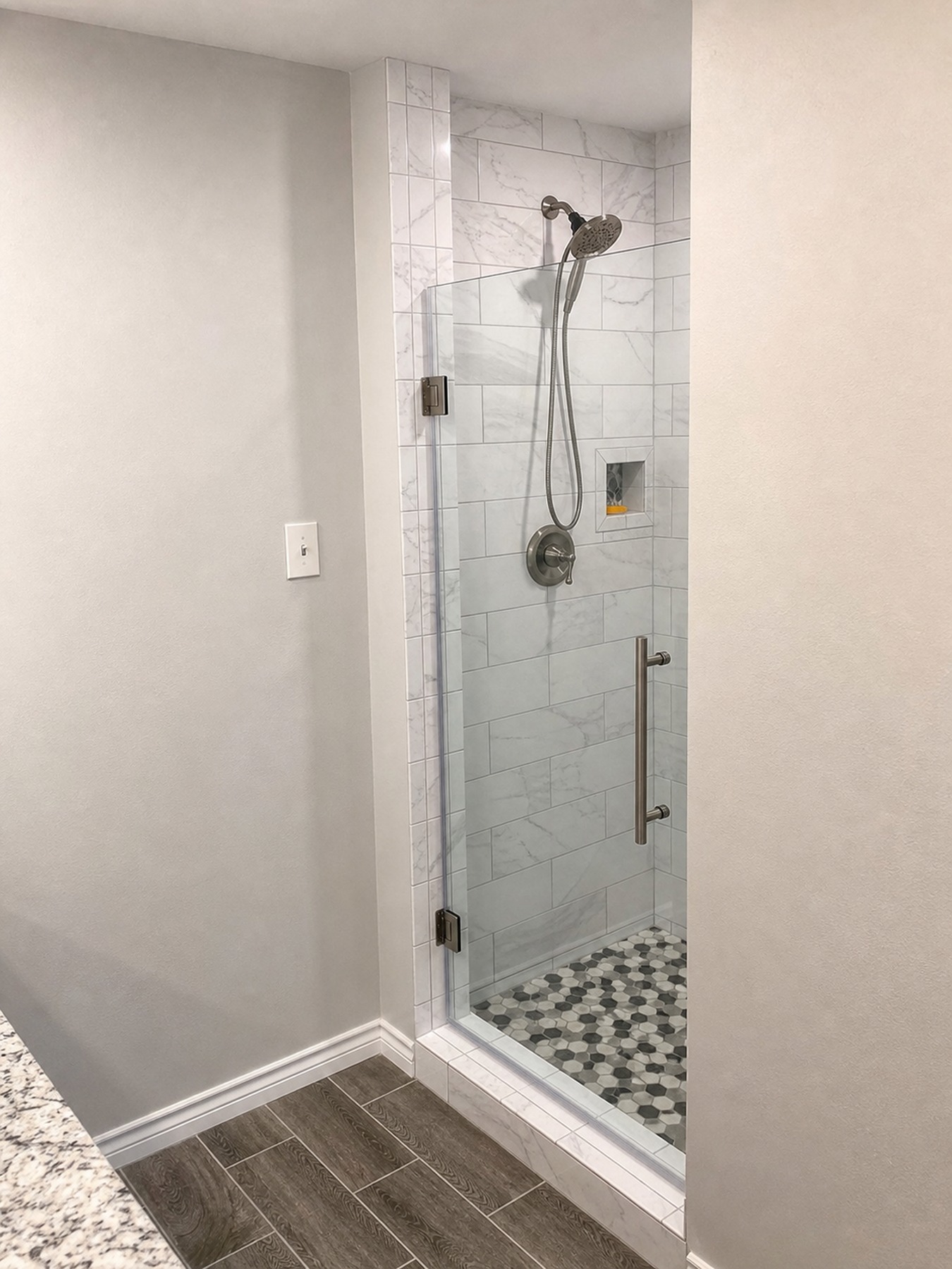 Finished glass shower entrance with gray marble-look wall tile