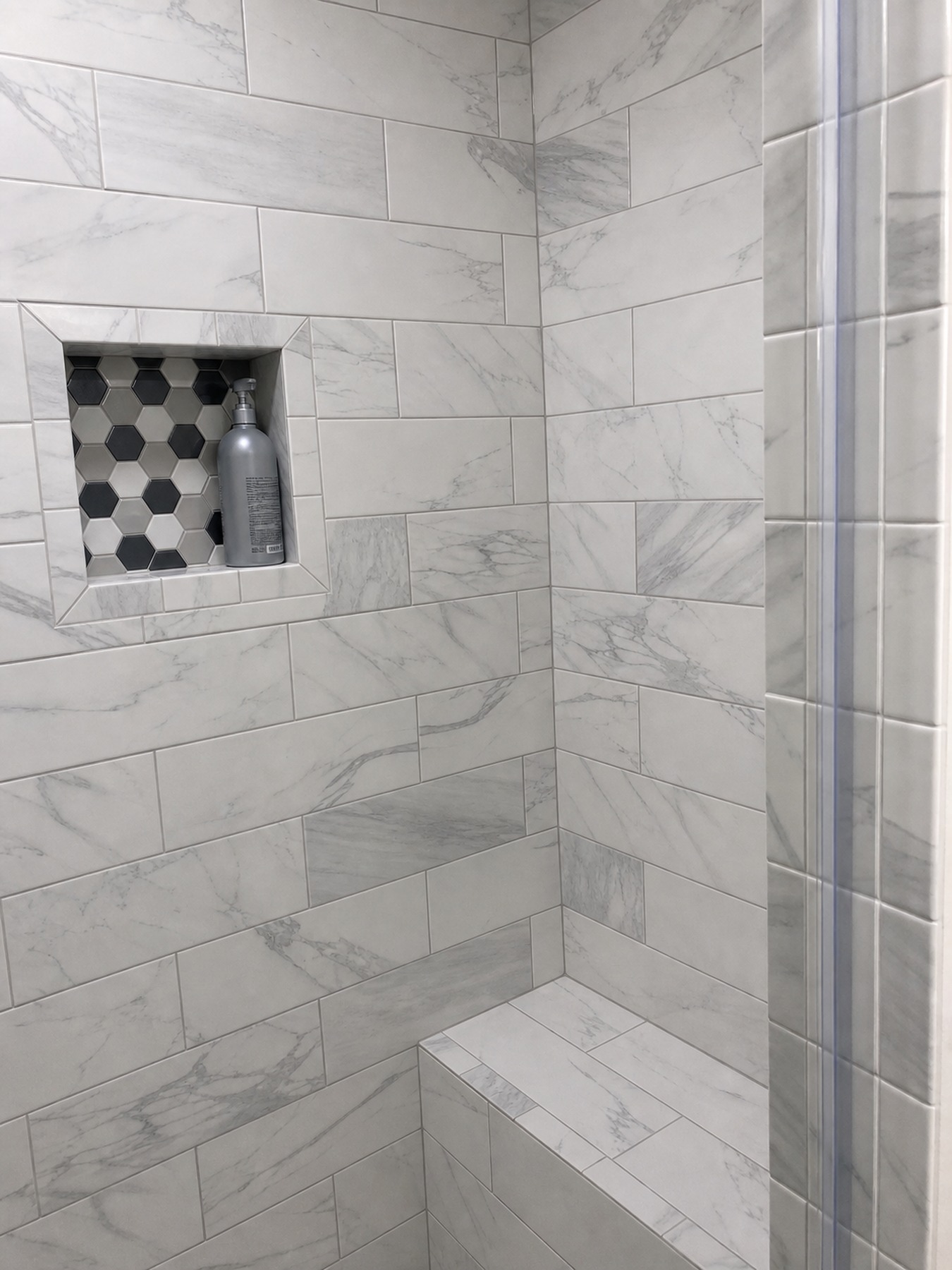 Shower bench and recessed niche detail with marble-look tile