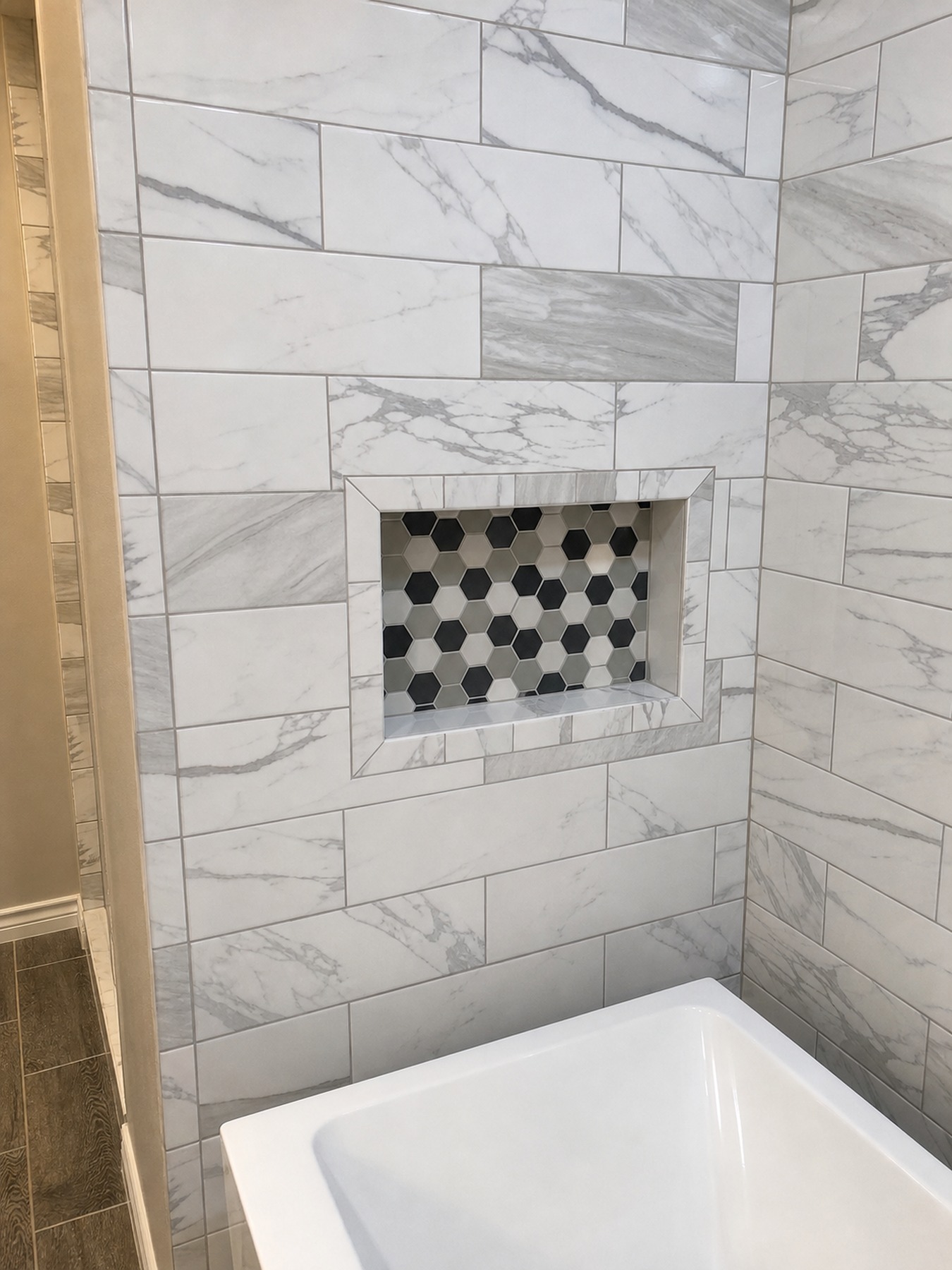 Tub shower niche detail with coordinated marble-look tile