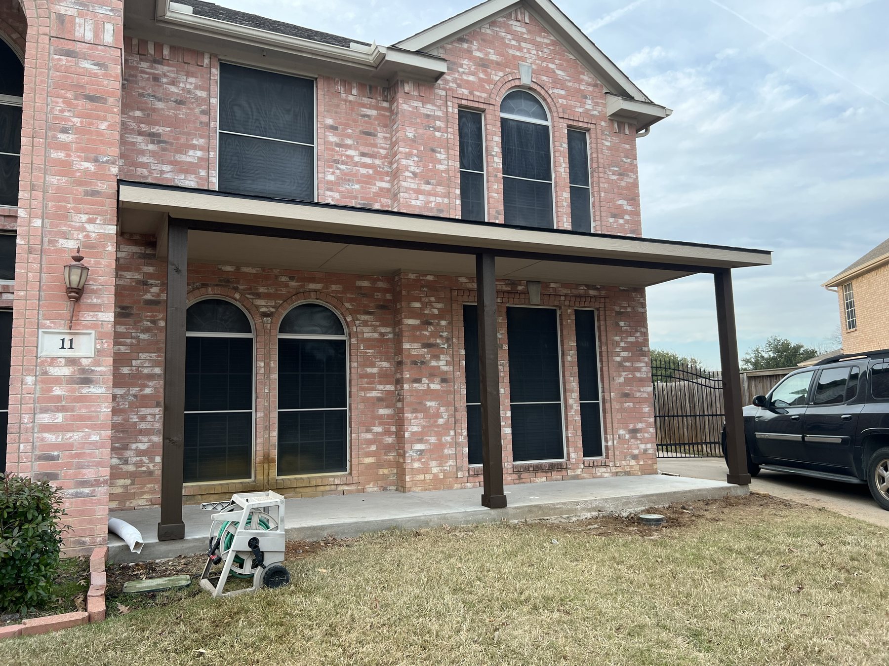 Finished covered front patio addition on a brick home