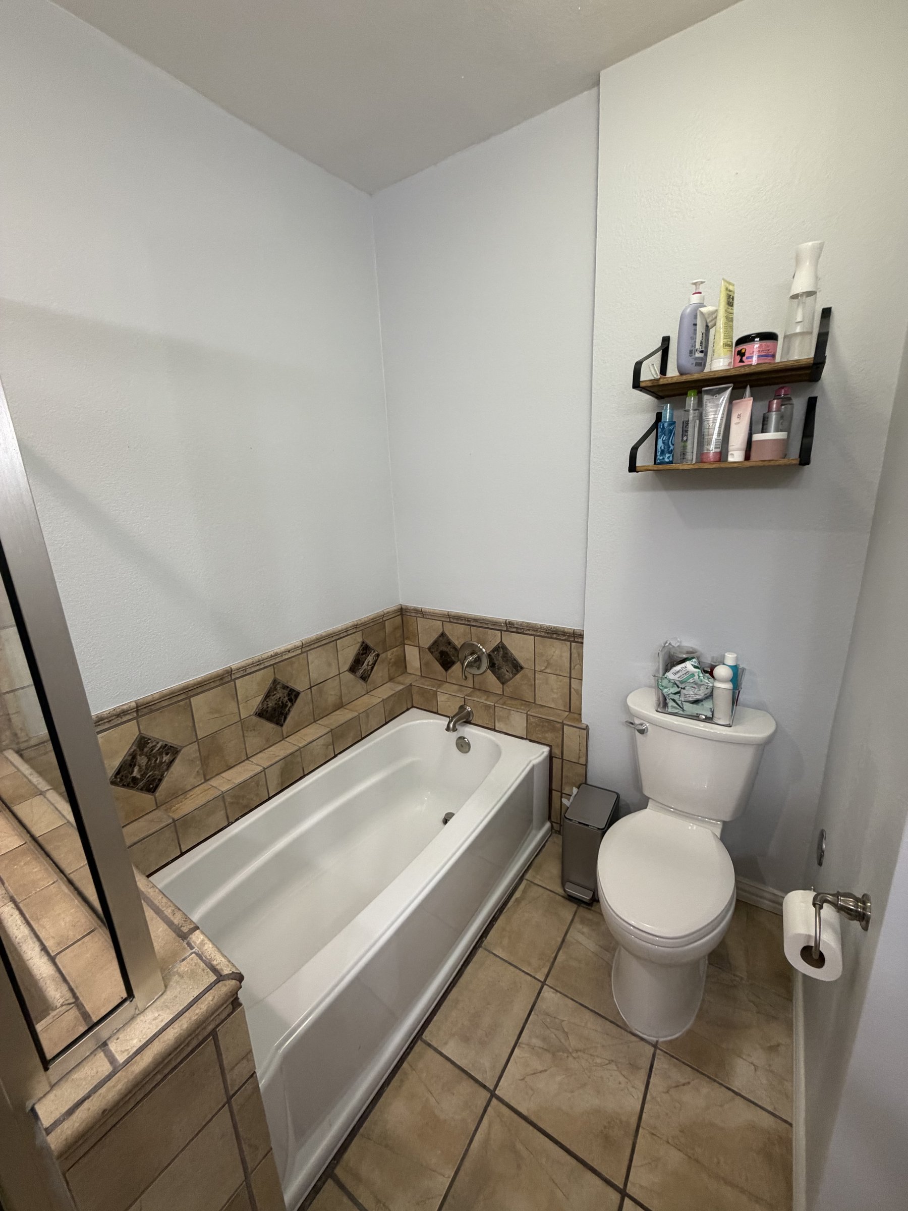 Original beige soaking tub and dated tile floor — before renovation