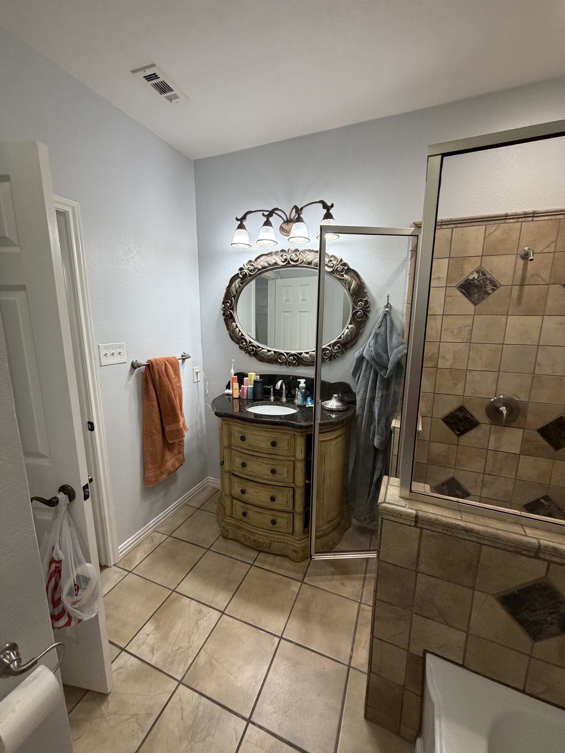 Old vanity area with gold oval mirror and beige cabinetry — before renovation